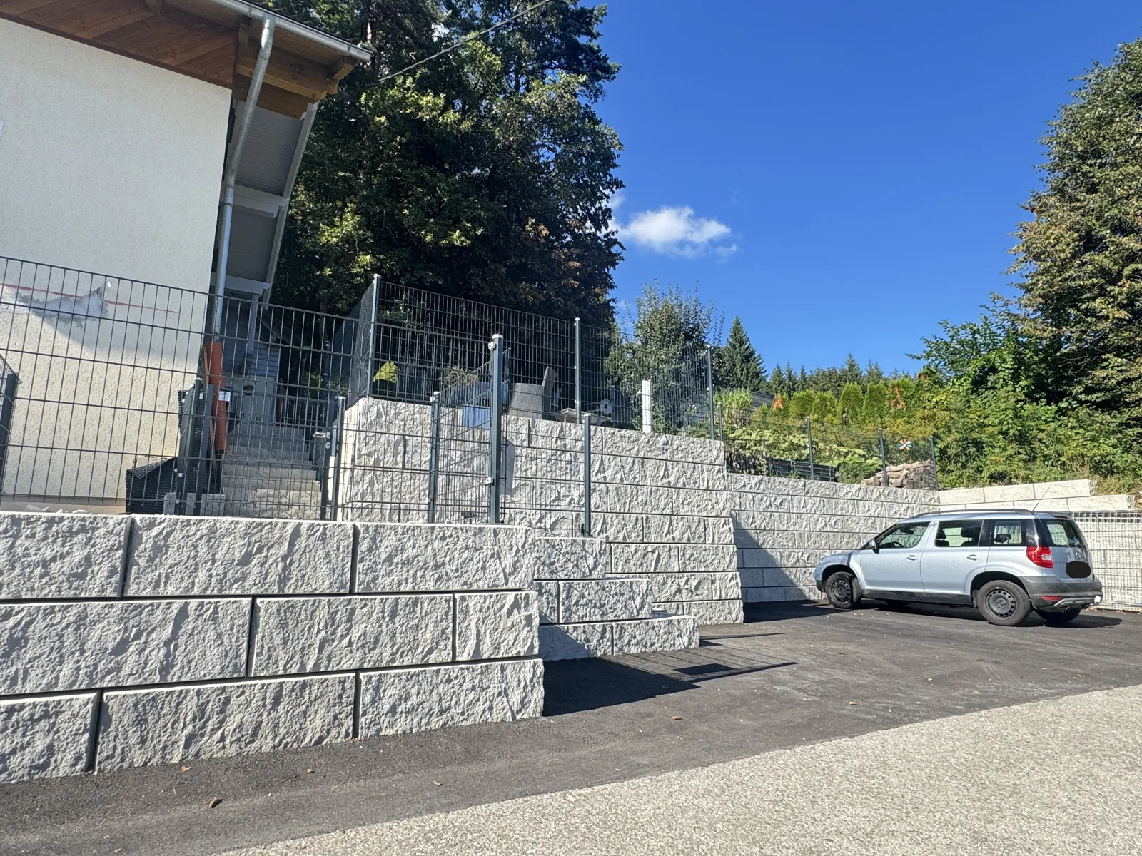 Stützwand aus ZEMROCK Betonfertigteilen an einer Außenanlage in Köttmannsdorf