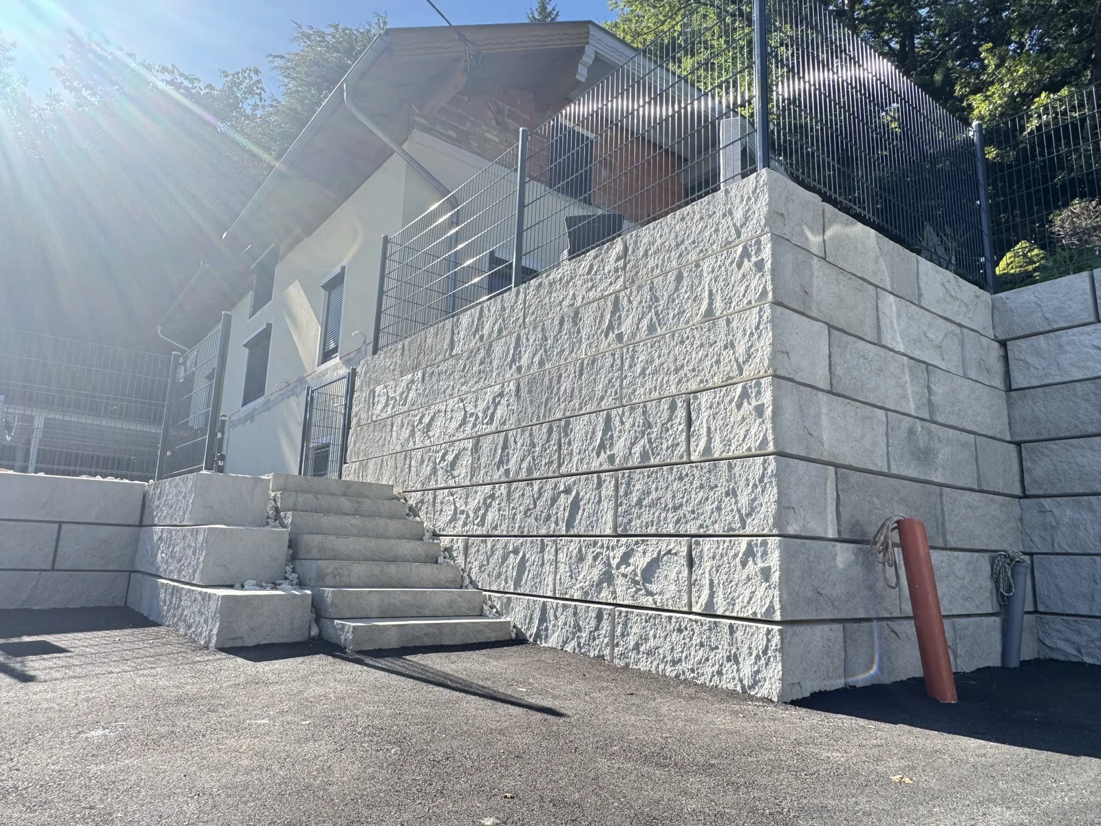 Hohe Stützwand aus ZEMROCK Betonfertigteilen mit Treppe zum Ausgleich eines Hanges