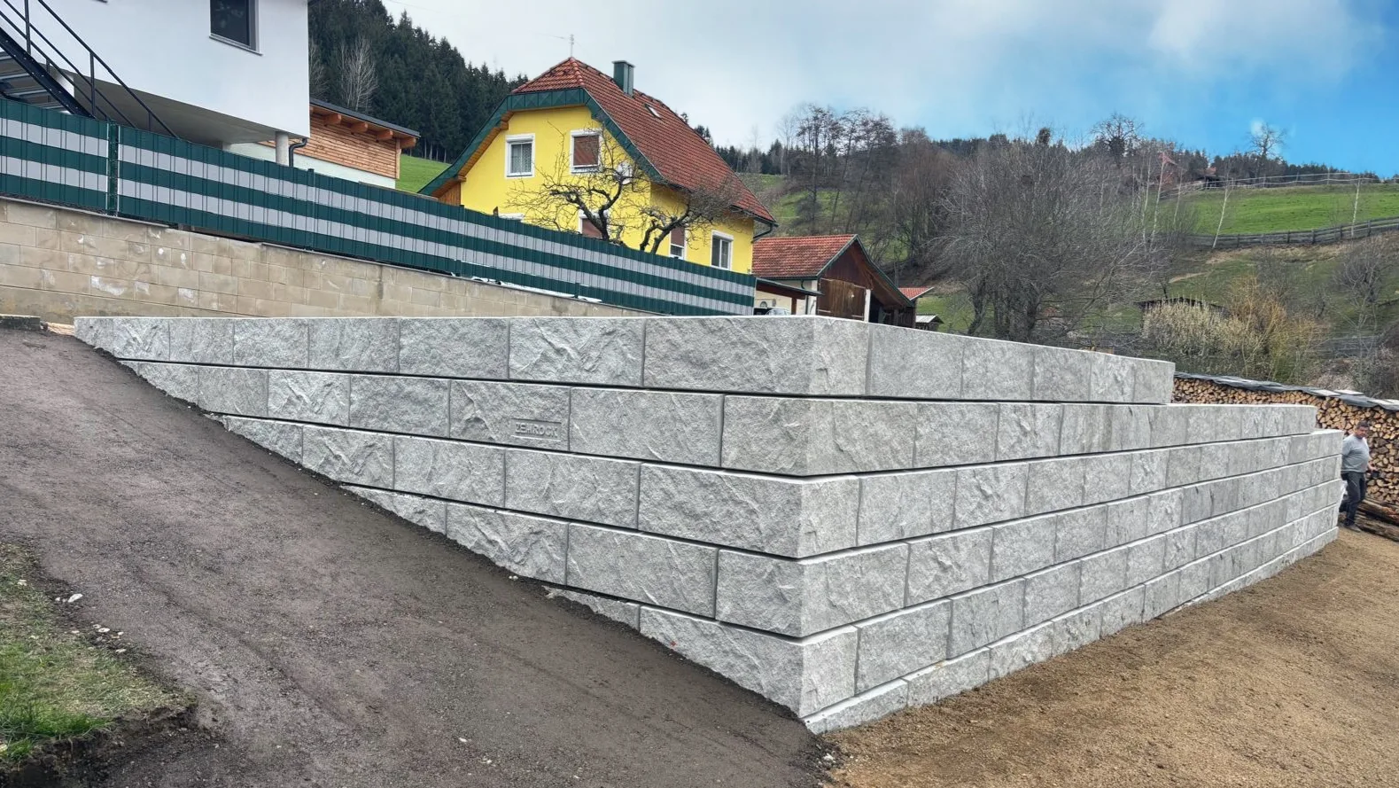 Lange Stützwand aus ZEMROCK Betonfertigteilen entlang einer befestigten Fläche